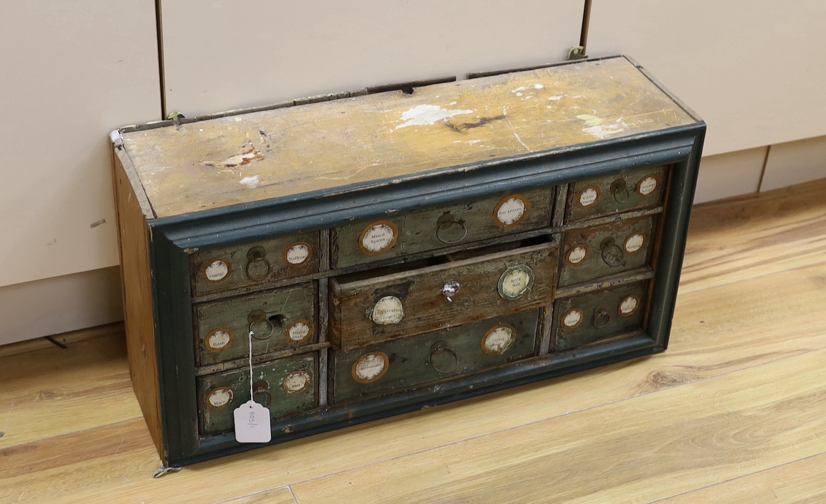 An early 20th century painted nine drawer spice hanging cupboard, 62cms wide, 31cms high